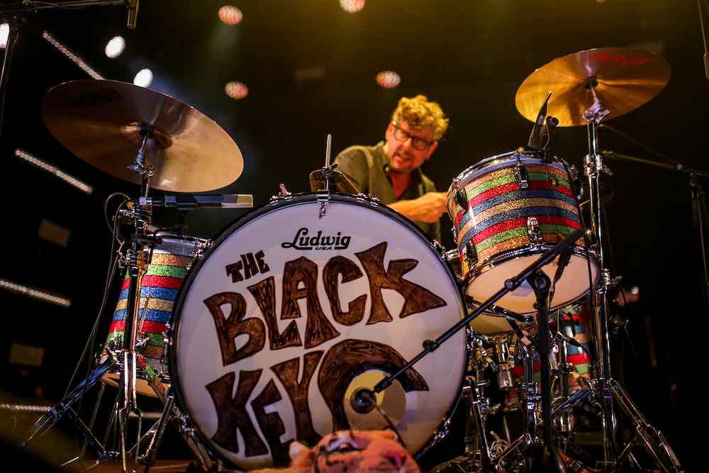 a drummer performs on stage at a nighttime concert.