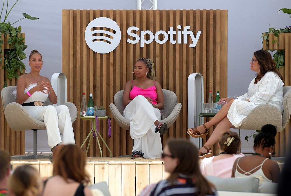 three women sit on a stage outdoors for a panel