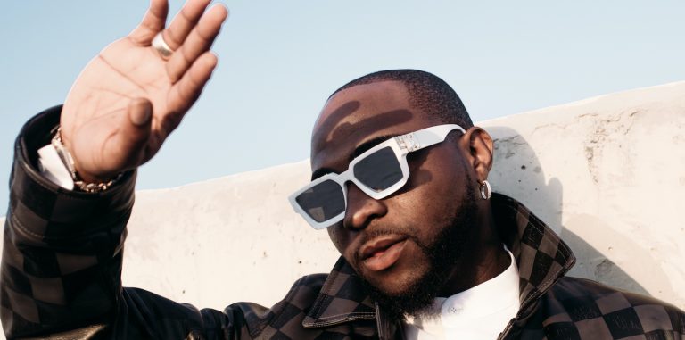 Davido holds his hands over his eyes to block the sun