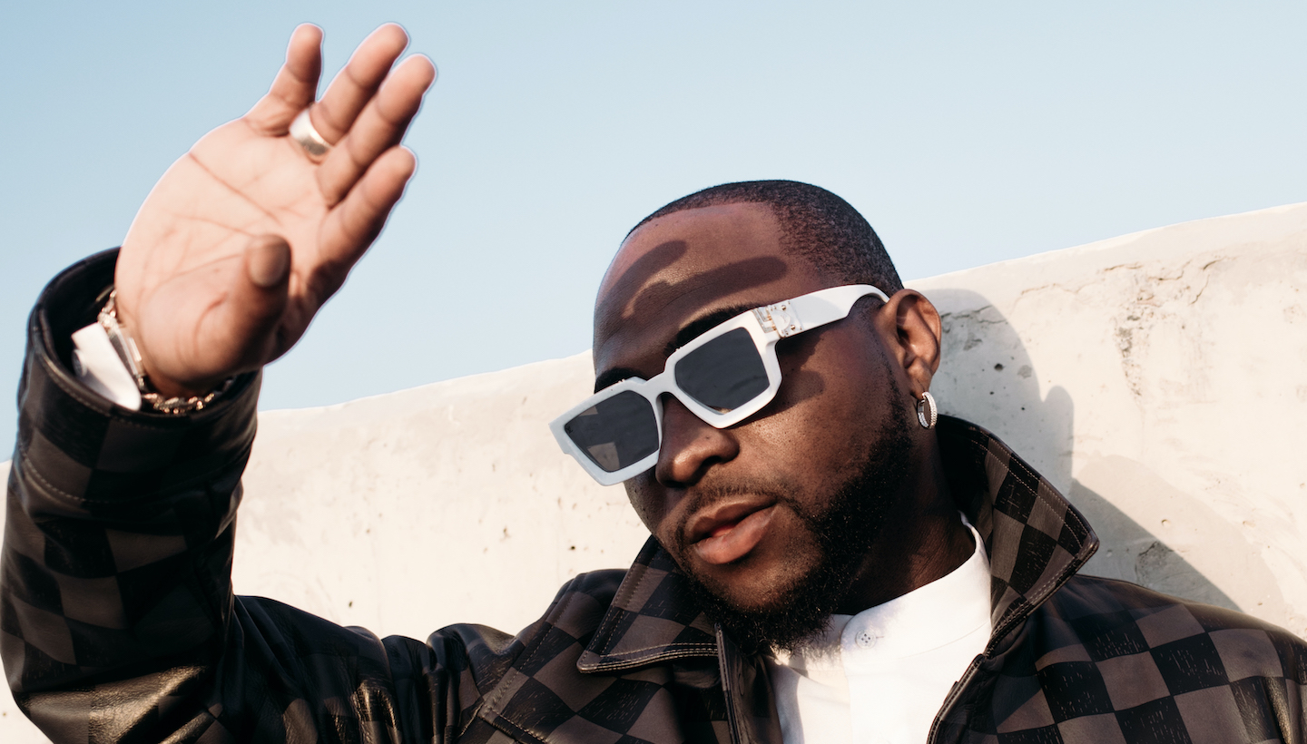 Davido holds his hands over his eyes to block the sun