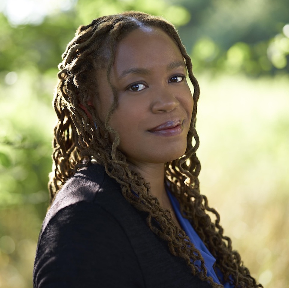 heather mcghee smiles in front of a green pastoral background