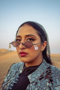 Raja Kumari wearing sunglasses and posing in front of the camera in the desert