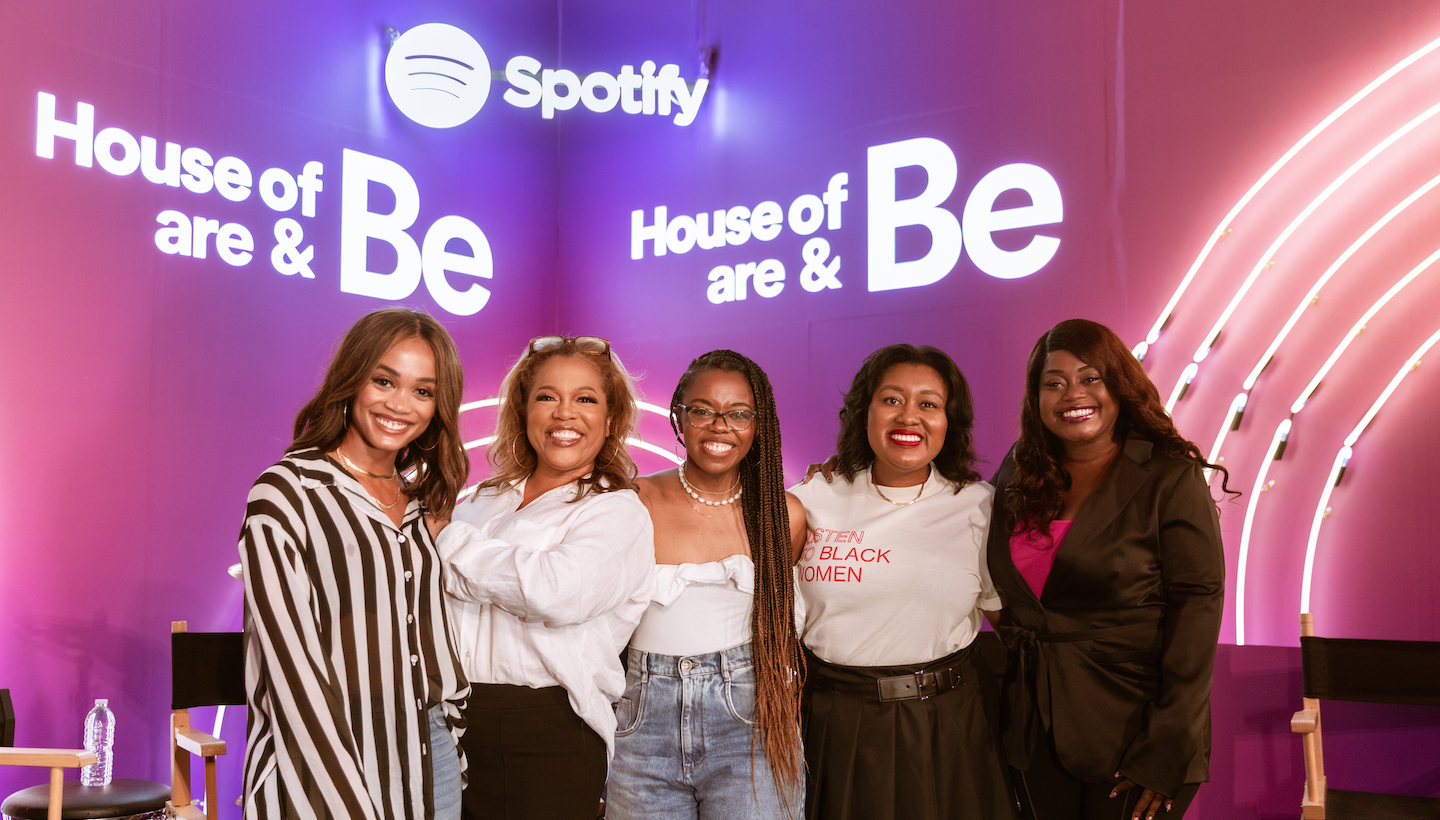 Panelists pose on stage in front of a camera