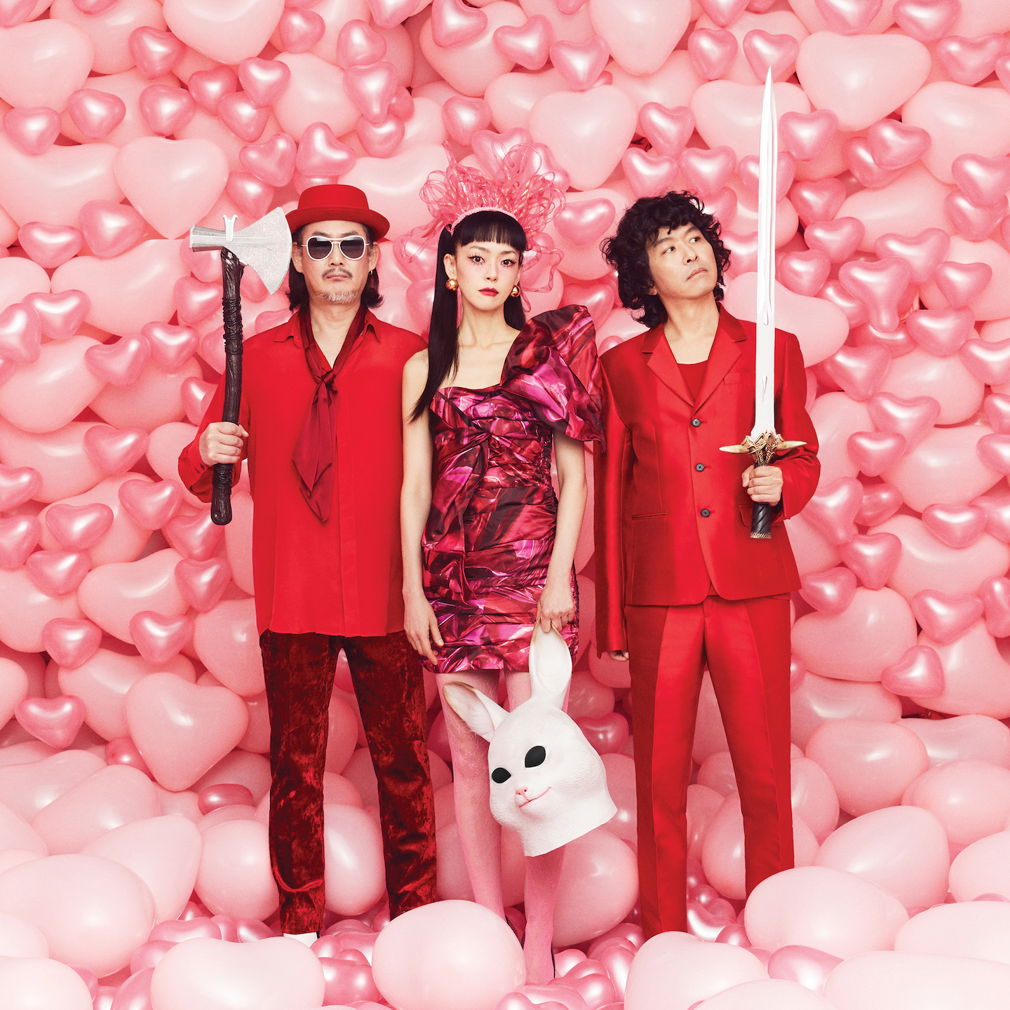 Jaurim band standing in a room filled with pink balloons. they are in red clothing attire and are holding various objects like a sword, rabbit mask, and axe