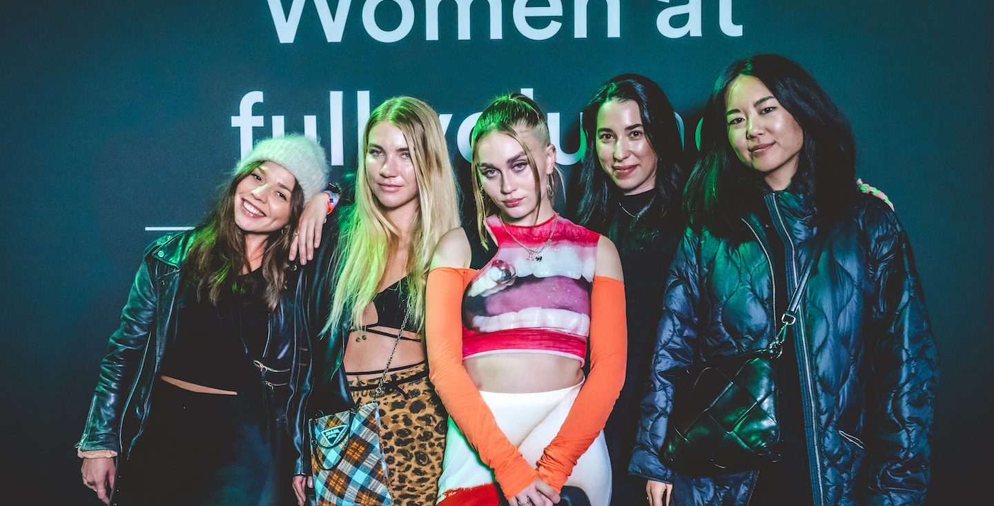 Five women posing in front of a camera at the music festival