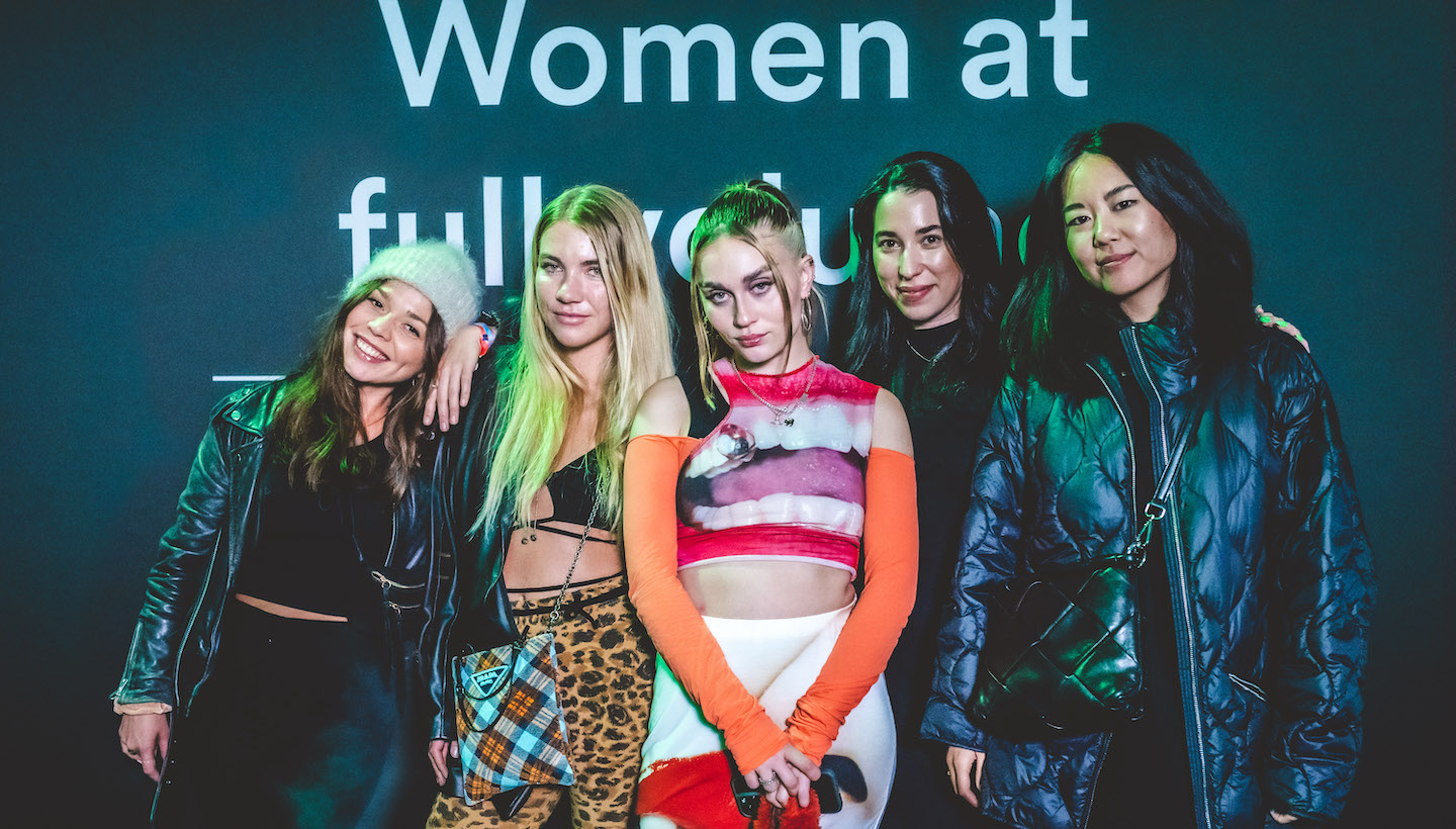 Five women posing in front of a camera at the music festival