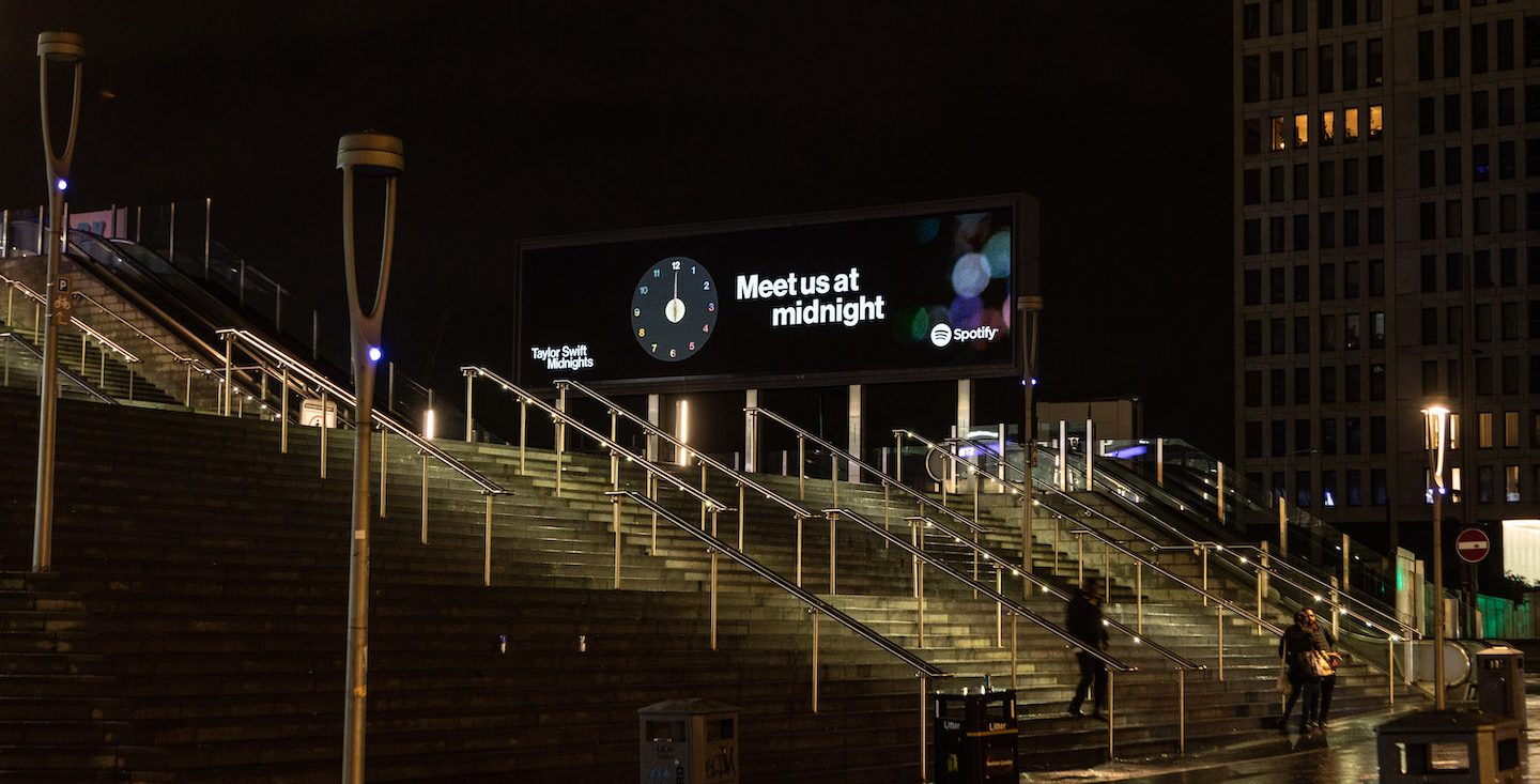 a photo of a digital billboard in london that says "meet me at midnight"