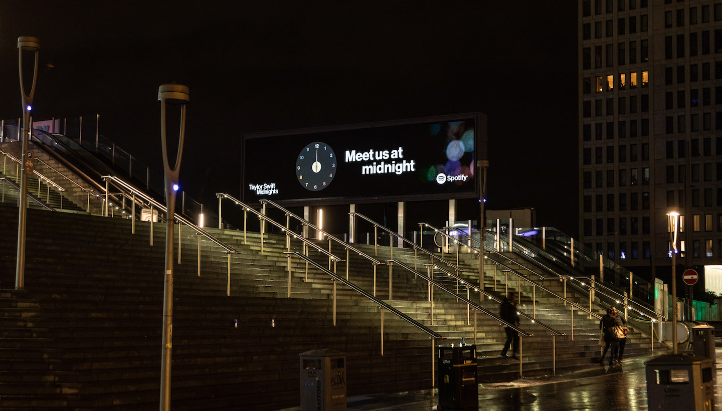 a photo of a digital billboard in london that says "meet me at midnight"