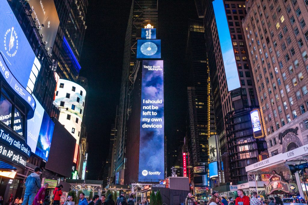 a photo of times square with a digital billboard showing lyrics from taylor swift's new album