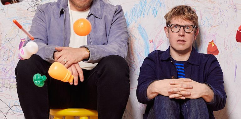 a photo of the parenting hell hosts sitting against a wall with toys thrown about