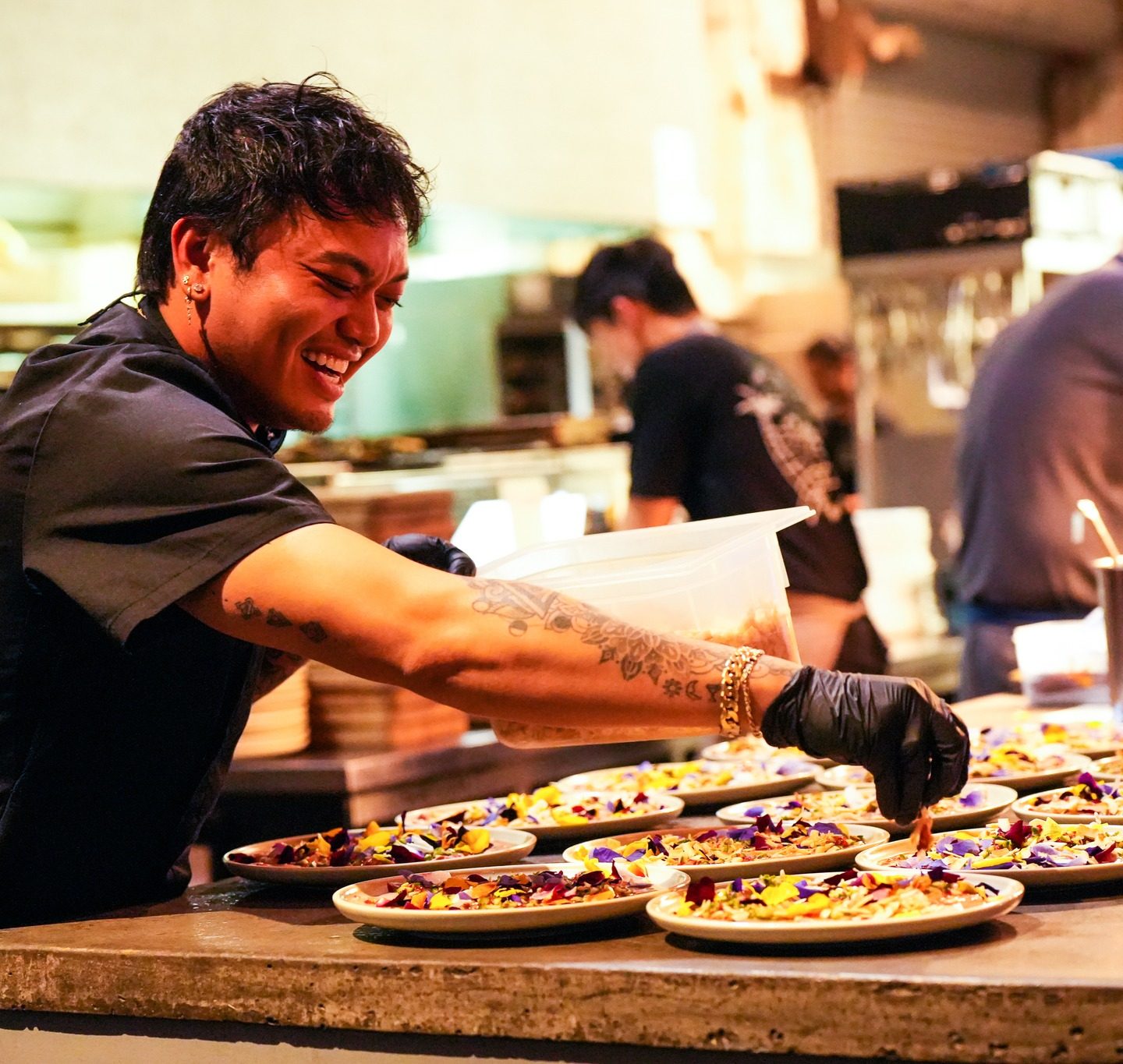 a chef putting the final touches on plates of food and sprinkles seasoning