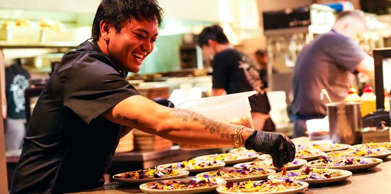 a chef putting the final touches on plates of food and sprinkles seasoning