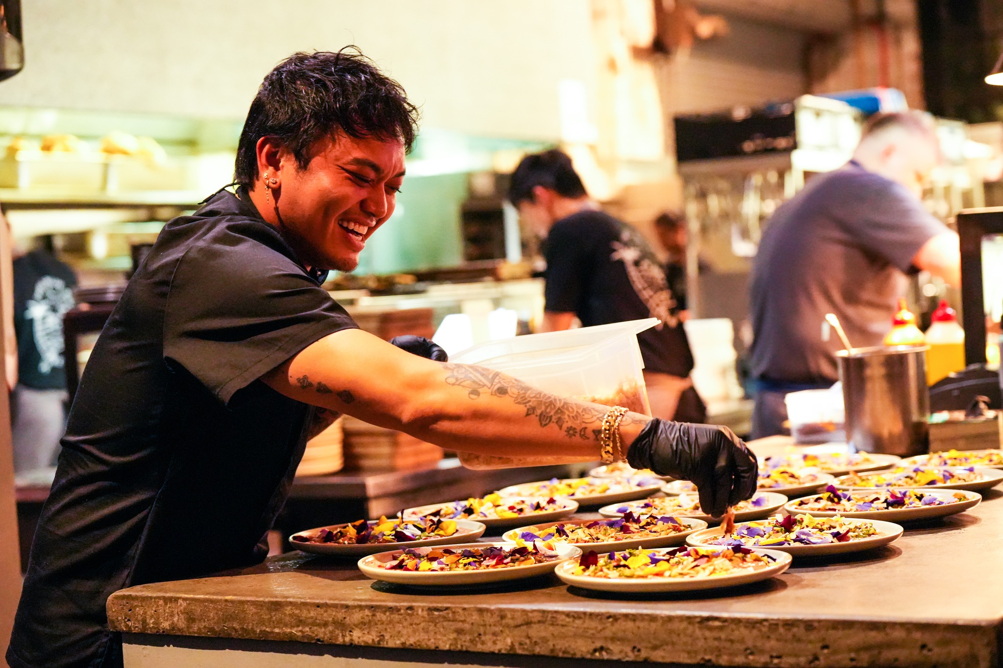 a chef putting the final touches on plates of food and sprinkles seasoning