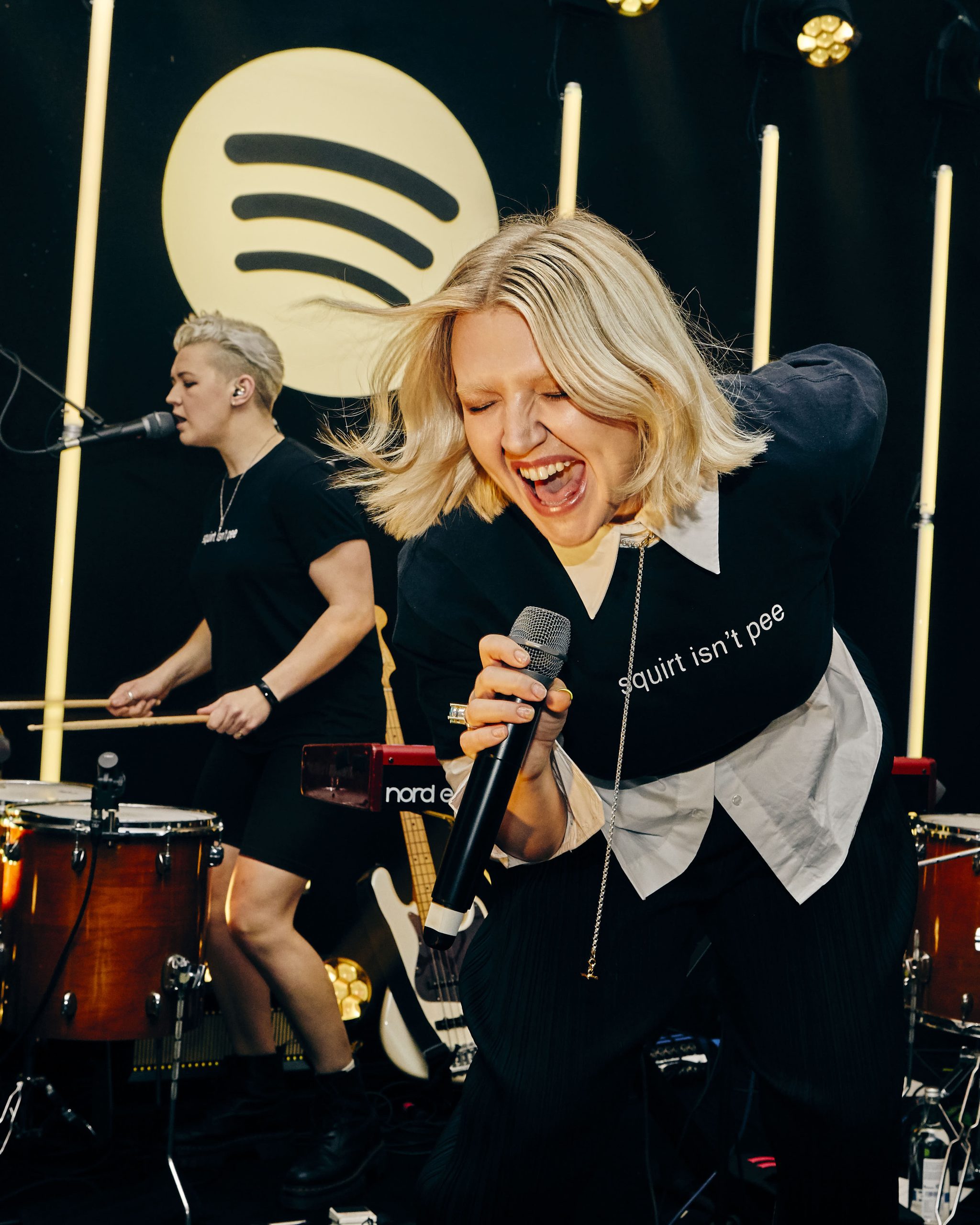 Pop singer, Self Esteem singing at a Spotify supper. Wearing a black sweatshirt and white button down 