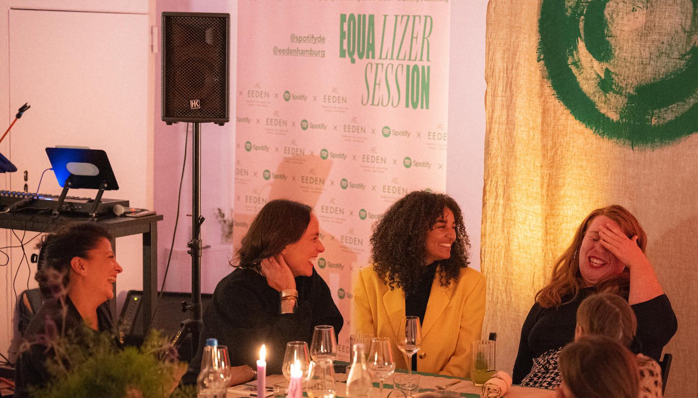 women sitting around a dinner table laughing at the spotify equalizer session. photo credit: swetlana holz