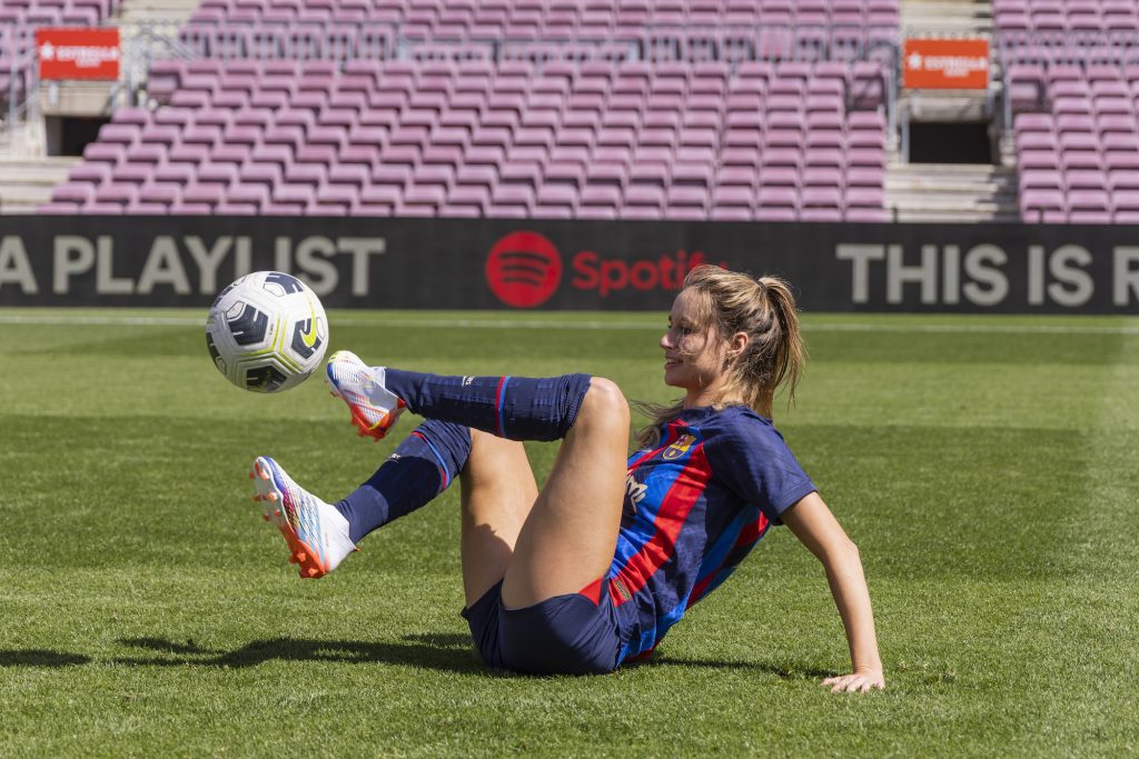 a woman is sitting on the ground kicking around the ball