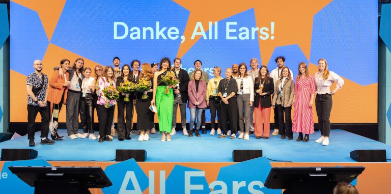 a group of participants standing on stage at the all ears summit