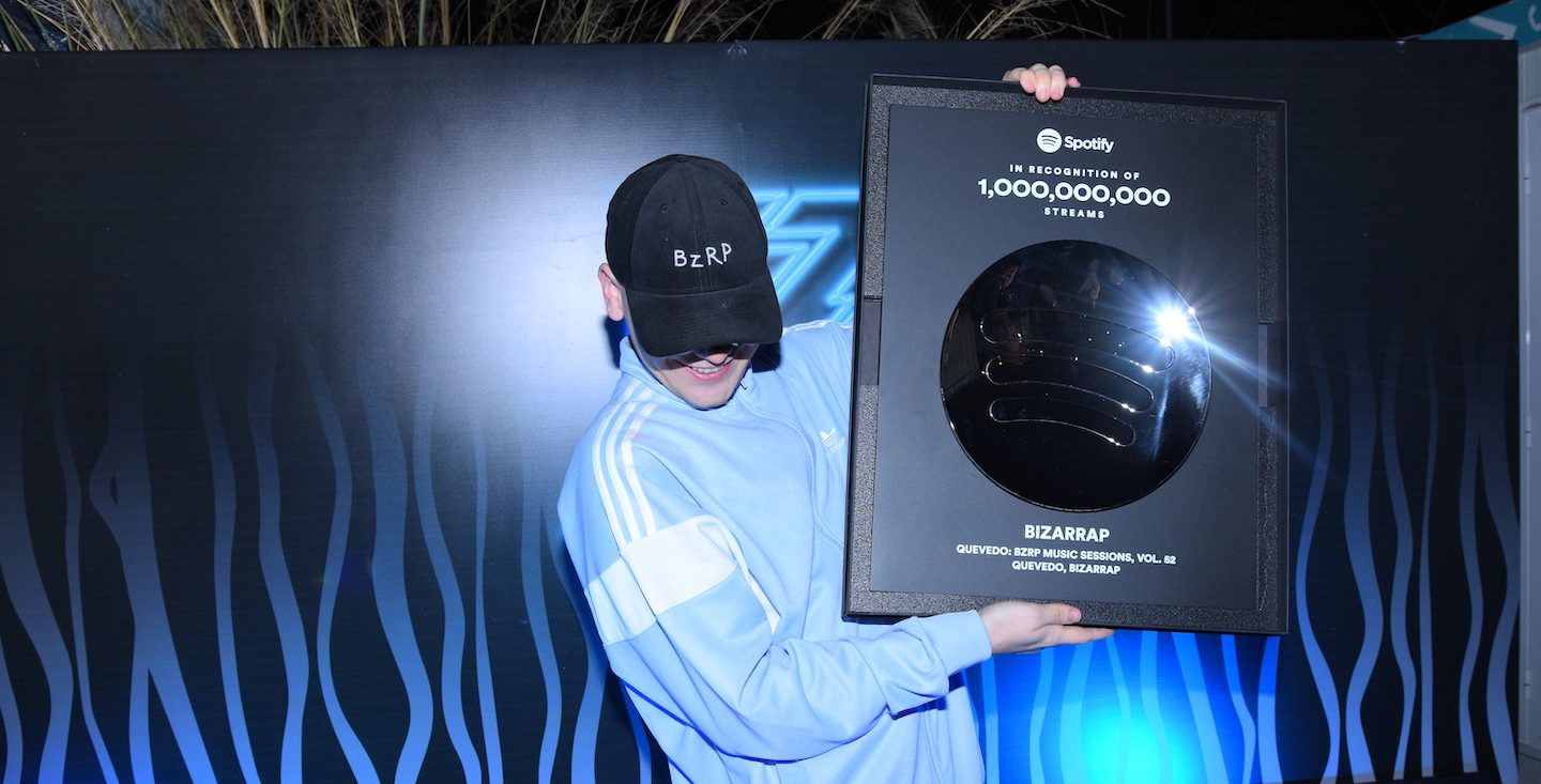 a photo of the artist bizarrap holding up his billions club plaque from spotify