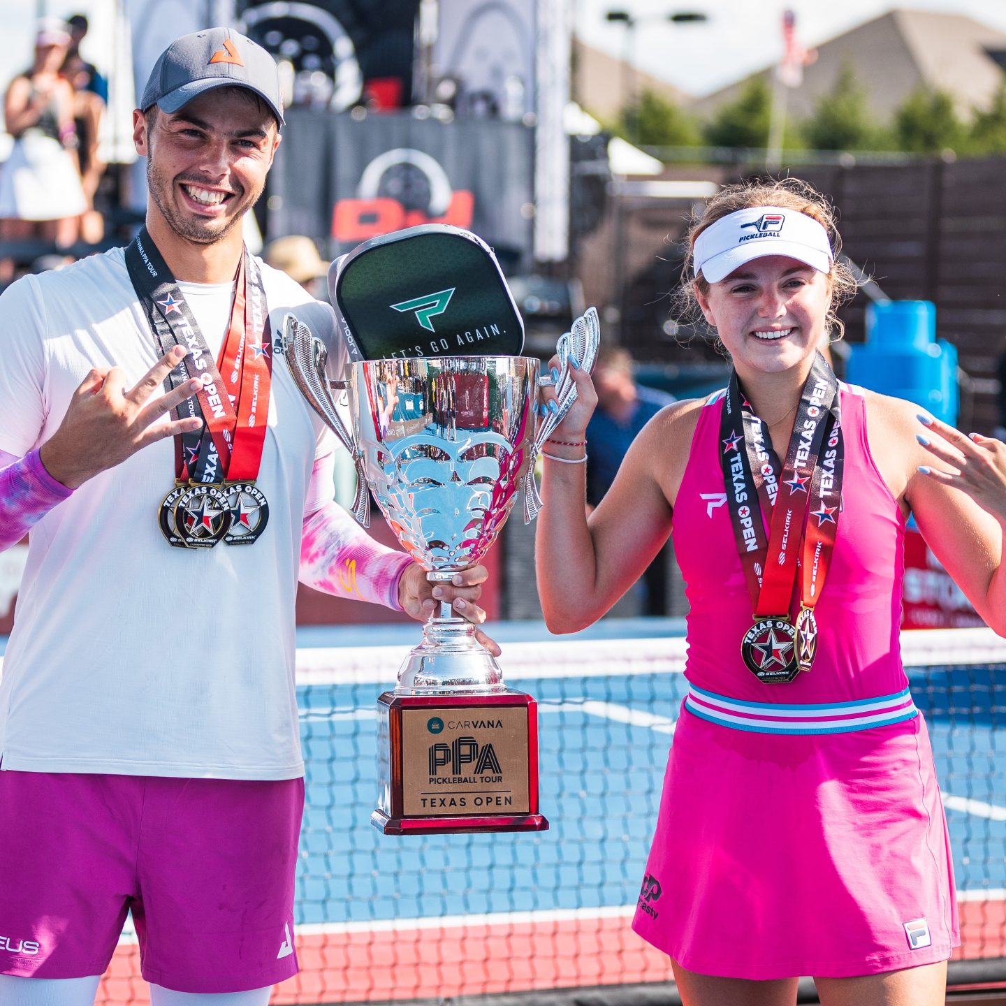 Ben Johns and Anna Leigh Waters posing with their trophy and medals.