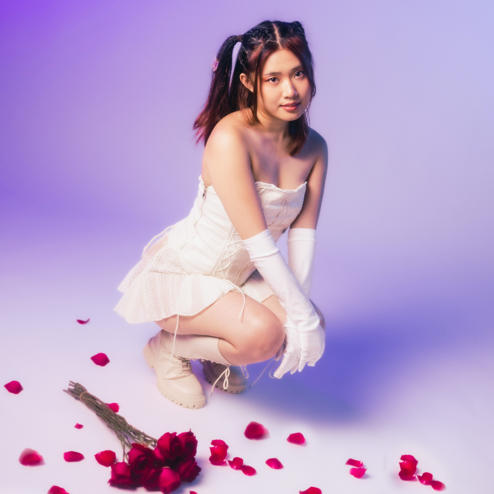 CLAUDIA posing in front of the camera on a purple backdrop with roses by her feet