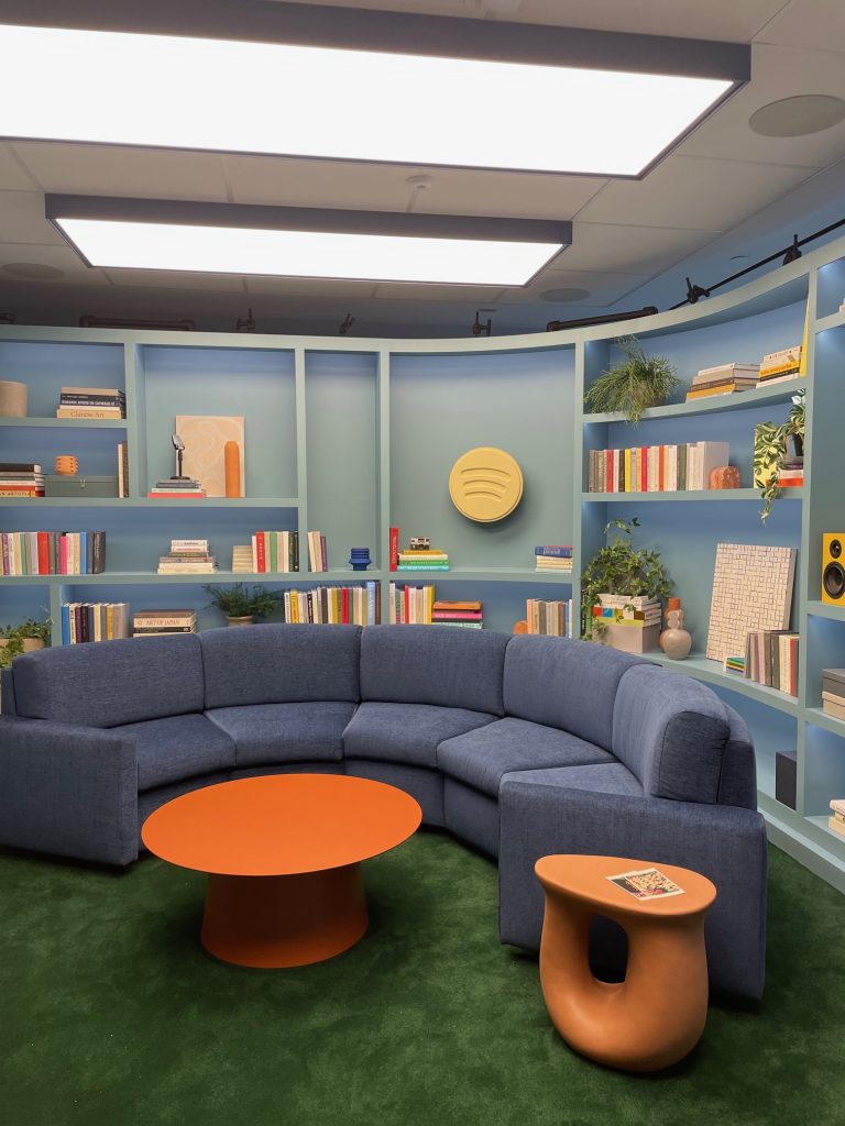 the whole room put together with bookshelf, blue couch, and orange table