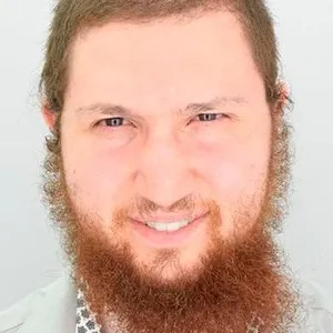 A very close-up portrait of Avraham Eisenberg, who has curly red hair and a beard