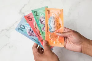 Photo of hands holding colorful banknotes denominated in 10 (blue), 5 (red), 2 (green), and 1 (orange).