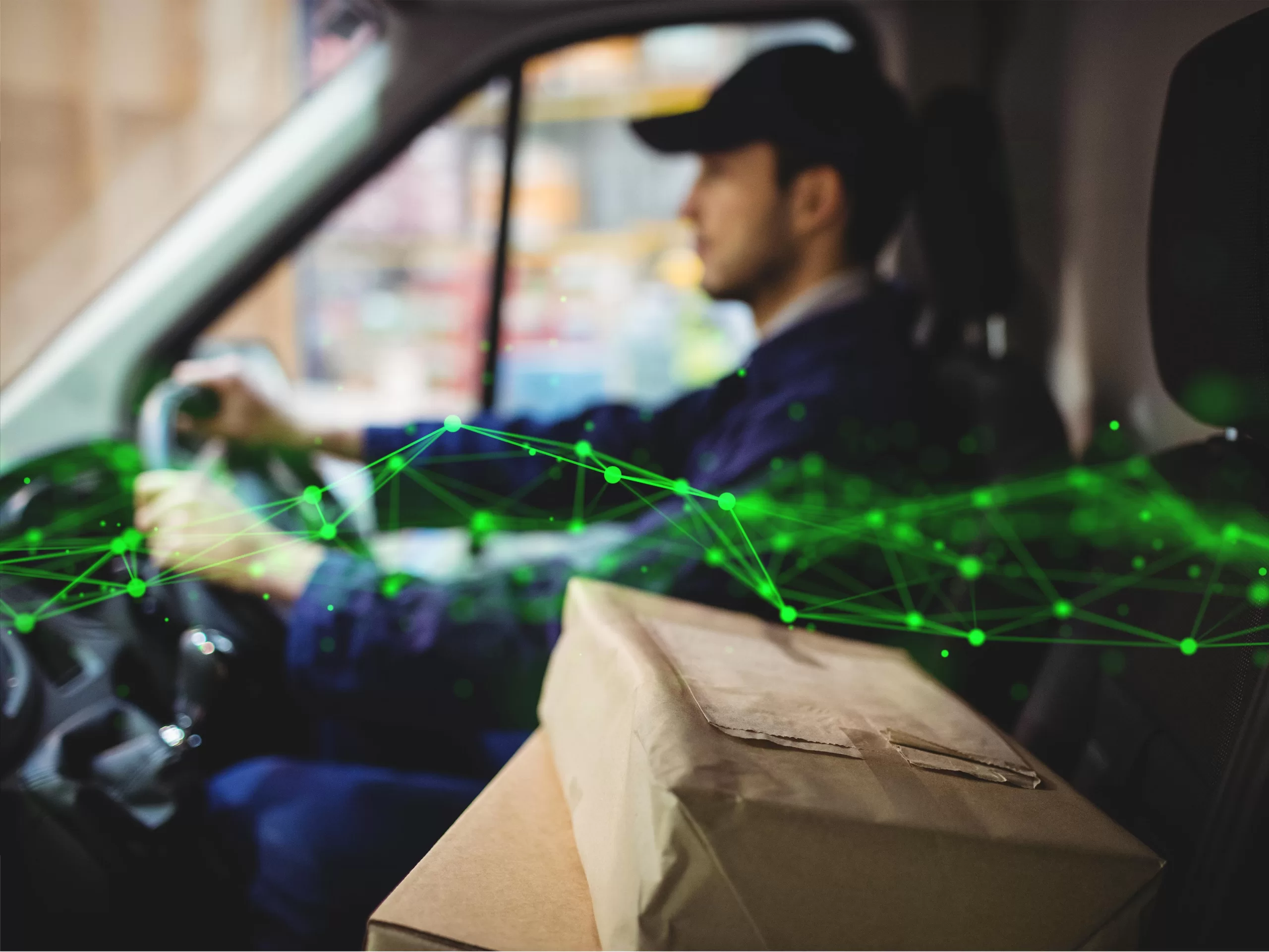Delivery driver driving van with parcels on seat outside warehouse