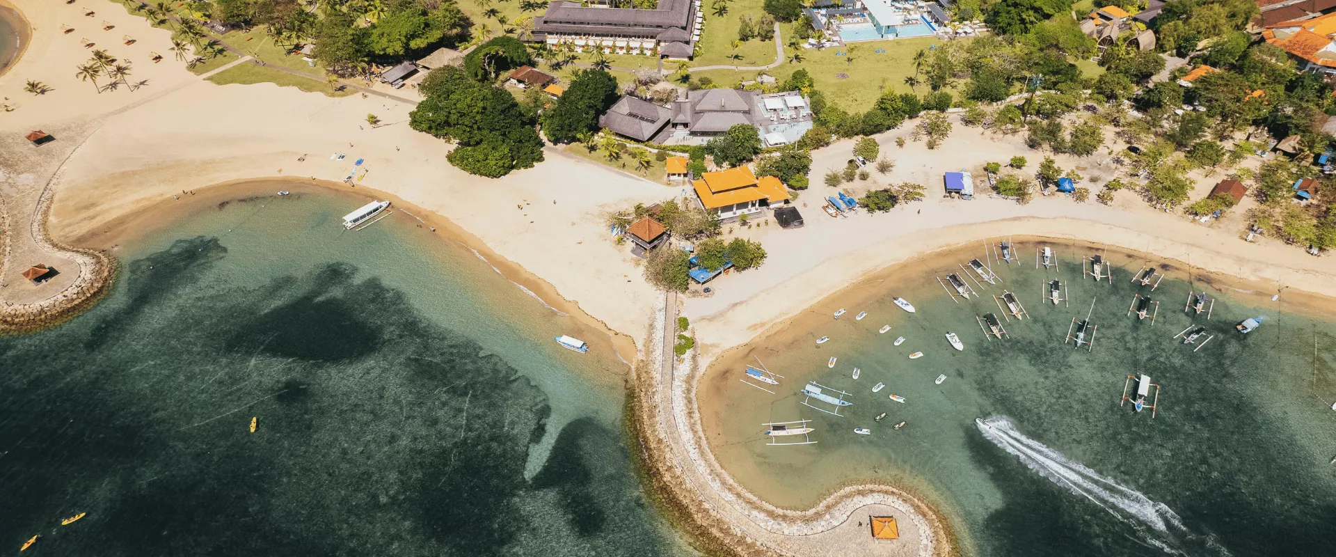 Aerial view of Club Med Bali beachfront resort surrounded by clear waters and tropical coastline, reflecting a memorable school holiday beach getaway for families.