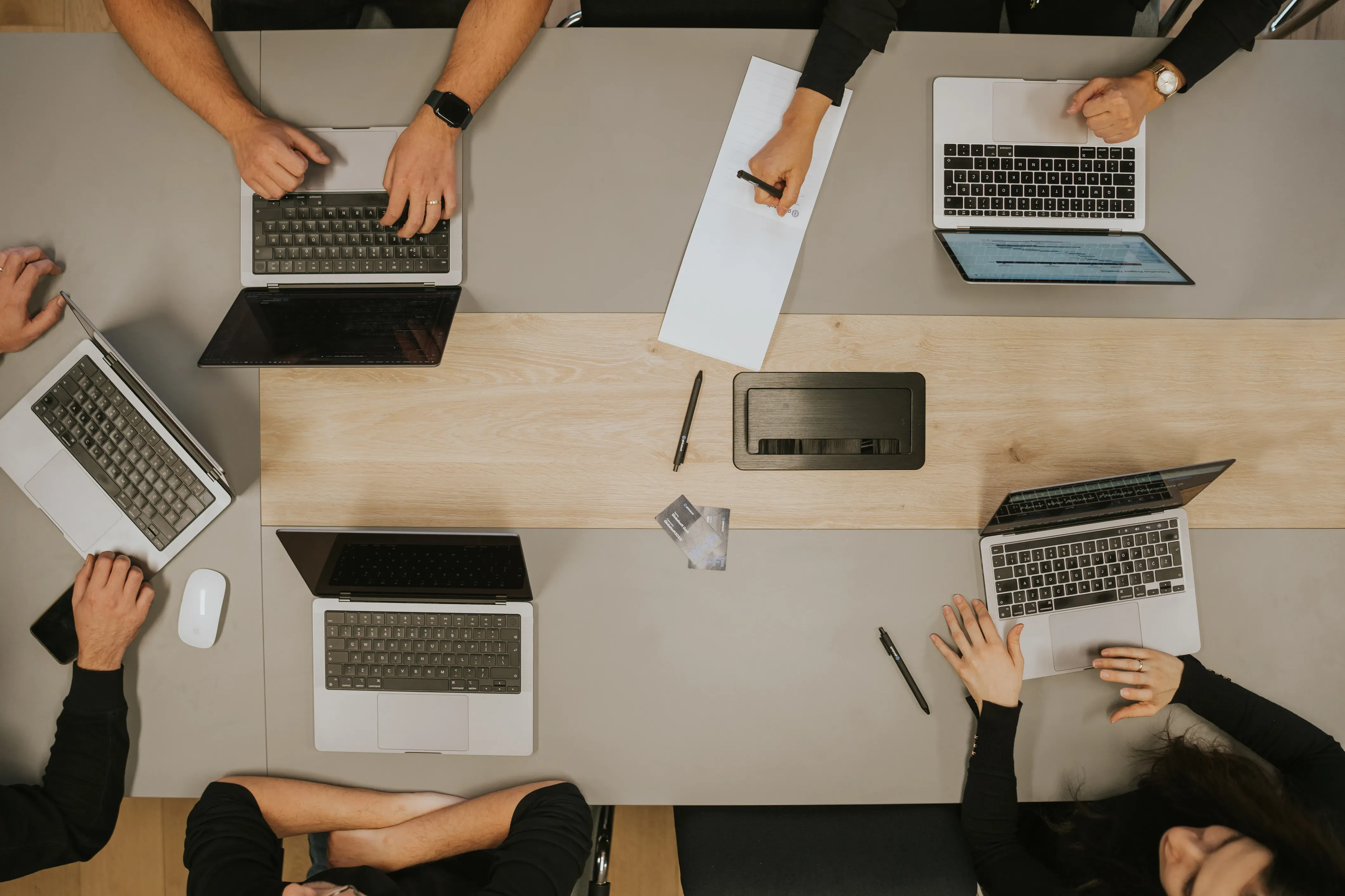 Team im Meeting mit Laptops und Notizblock