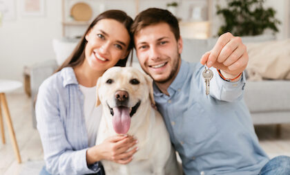 A couple and their retriever pose with their new house key.