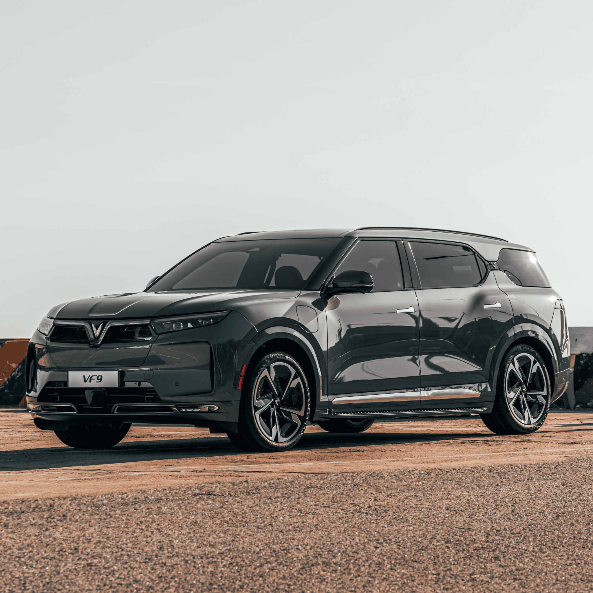  A shiny new VinFast VF 9 with an impressive EP EV range is parked on a red dirt road on a sunny day.