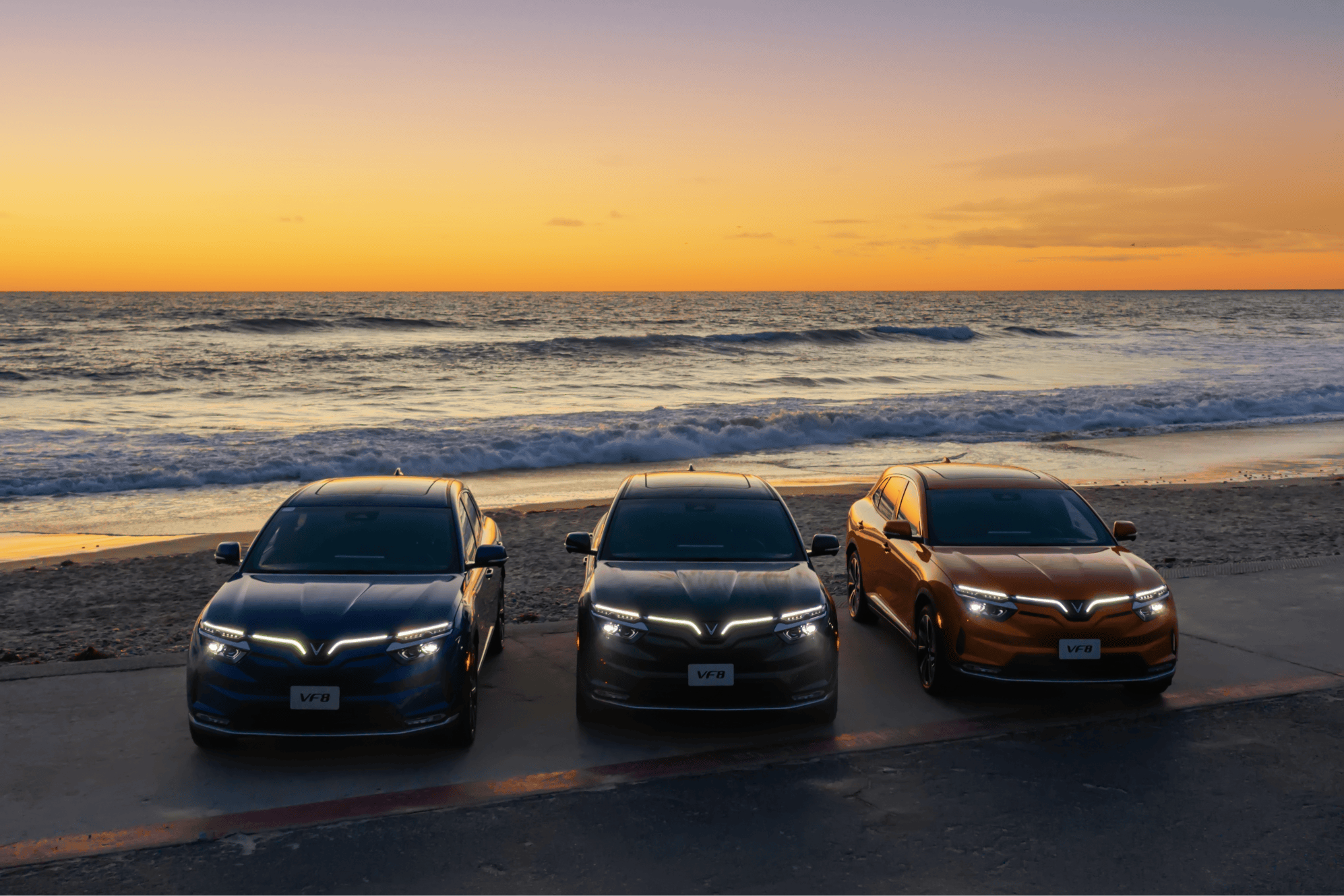 Three VinFast VF 8 cars are parked on the beach during the sunset to promote the California clean vehicle rebate project.