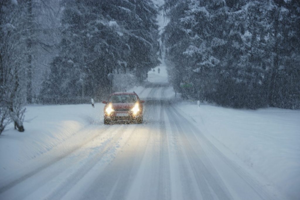 A regular passenger car driving in the snow with caution in the middle of the country. About 33% of American drove less due to the cost of gas and 19% of the drivers plan to drive more during the holidays. ALTRENDO IMAGES/SWNS TALKER