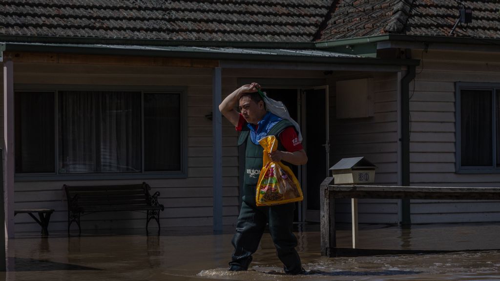 A resident in the suburb of Maribyrnong walks down a flooded street on October 14, 2022 in Victoria, Australia. An emergency warning was issued for Maribyrnong this morning with residents near the river told to evacuate homes as flood waters rise following heavy rain. (Photo by Asanka Ratnayake/Getty Images)