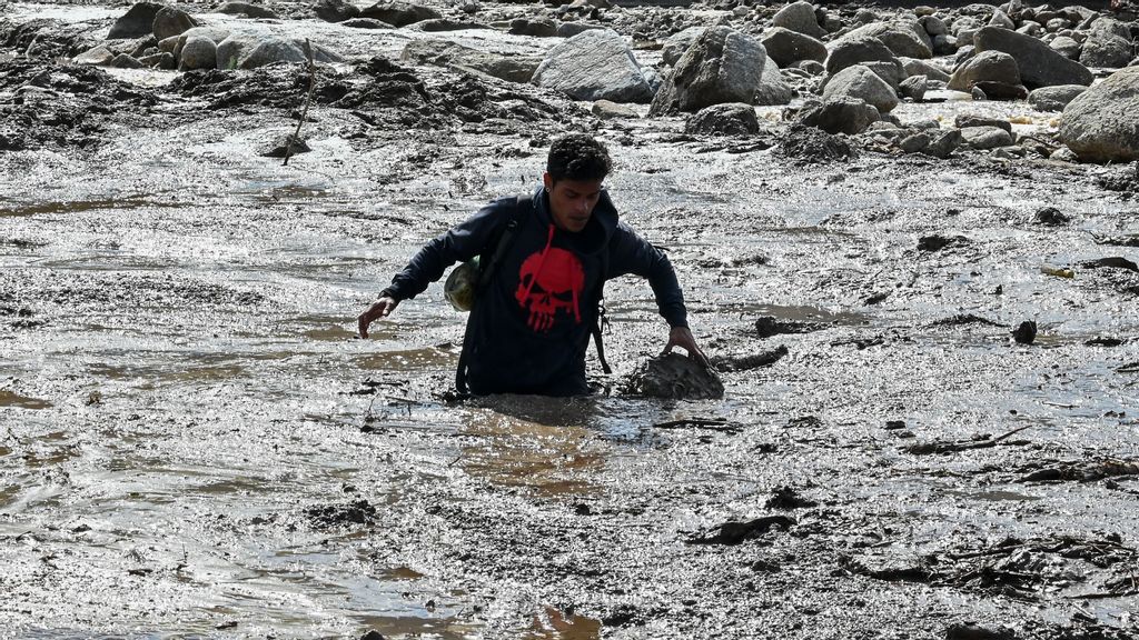 A man walks in deep mud and debris in El Castaño, a neighbourhood in Maracay, the capital of the Venezuela northern Aragua State, on October 18, 2022, a day after intense rain caused floods and a mudslide that killed at least three people. FEDERICO PARRA VIA GETTY IMAGES