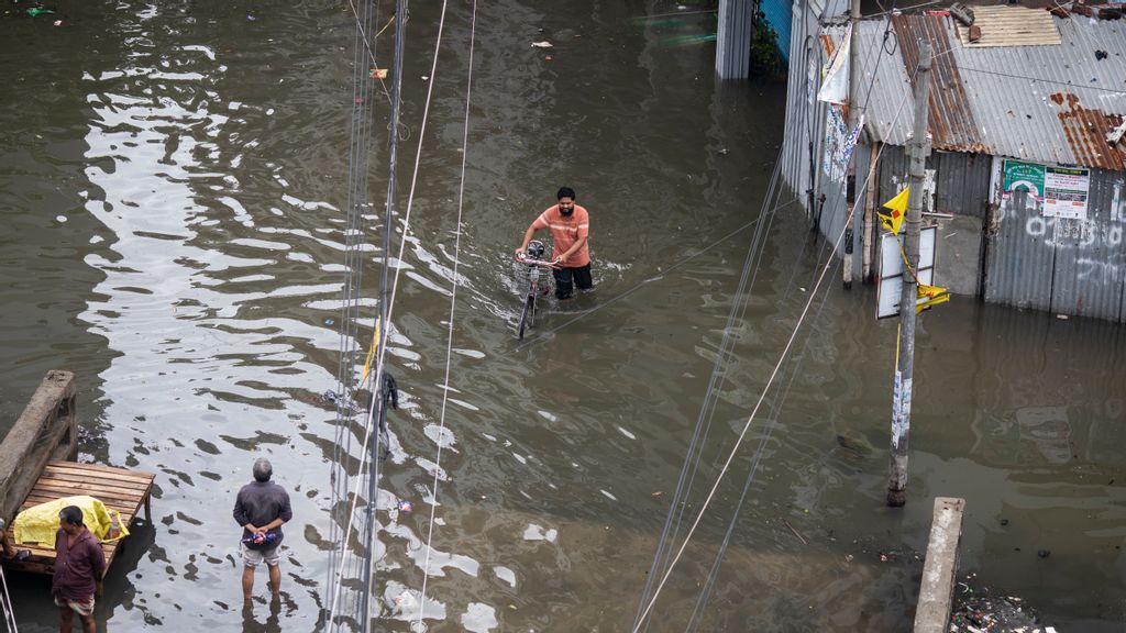 2022/10/25: A man moves through a waterlogged street following heavy rains causing much suffering for pedestrians and commuters. Cyclone Sitrang hits Bangladesh snapping communications and power links, flooding streets bringing activities to a stand still. (Photo by Sazzad Hossain/SOPA Images/LightRocket via Getty Images)