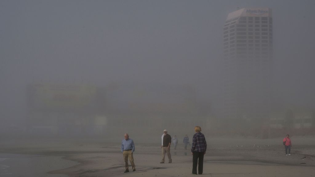 People walk on the beach near Steel Pier on a foggy morning in Atlantic City, New Jersey on October 26, 2022. - Ten years after the devastating hurricane Sandy, the seaside town of Atlantic City, on the American east coast, has fortified its famous promenade between its casinos and the Atlantic Ocean. PHOTO BY ANGELA WEISS VIA AFP/GETTY IMAGES