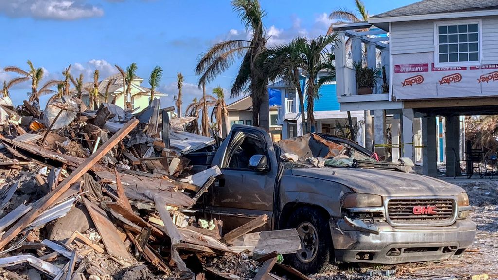 A destroyed truck is seen near a pile of debris in Fort Myers Beach, Florida a month after Hurricane Ian made landfall on September 28 as a Category 4 hurricane, causing an estimated $67 billion in insured losses and at least 127 storm-related deaths in Florida. PHOTO BY PAUL HENNESSY VIA GETTY IMAGES