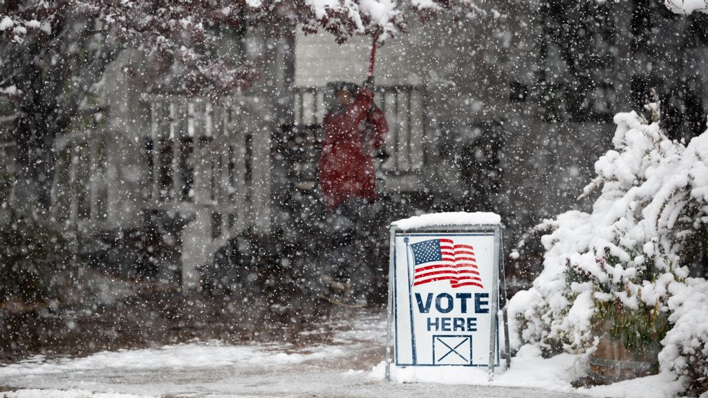 A Washoe County employee uses a shovel to knock snow off of trees outside of a vote center on November 8, 2022 in Reno, Nevada. After months of candidates campaigning, Americans are voting in the midterm elections to decide close races across the nation. PHOTO BY TREVOR BEXON VIA GETTY IMAGES