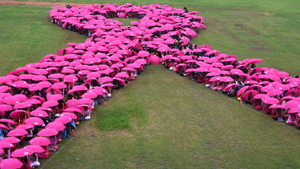 College students hold umbrellas to make a formation of pink ribbon during a breast cancer awareness campaign in Chennai on October 31, 2022. Israel scientists have found a way to limit breast cancer relapses 88%.  PHOTO BY ARUN SANKAR/AFP VIA GETTY IMAGES