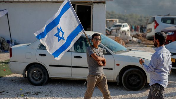 Israeli settlers march in a newly-built settler outpost in the occupied West Bank, on June 21, 2021. Right-wing activists and settler leaders held 14 simultaneous marches to stop illegal Arab control in Area C. AHMAD GHARABLI/AFP VIA GETTY IMAGES