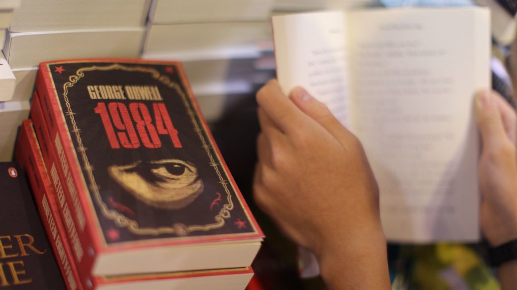 A boy reads a book next to copies of British writer George Orwell's 1984 at Hong Kong's annual book fair on July 15, 2015. The 26th edition of the fair showcased a record number of over 580 exhibitors from 33 countries and regions. George Orwell's 1984 has topped the bestseller list in Russia, during a year plagued by President Vladimir Putin's invasion of Ukraine. AARON TAM/BENZINGA