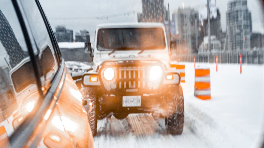 Shot of a Jeep in the mirror of a car during a snowy day in Vancouver (Alejandro Luengo/Unsplash)