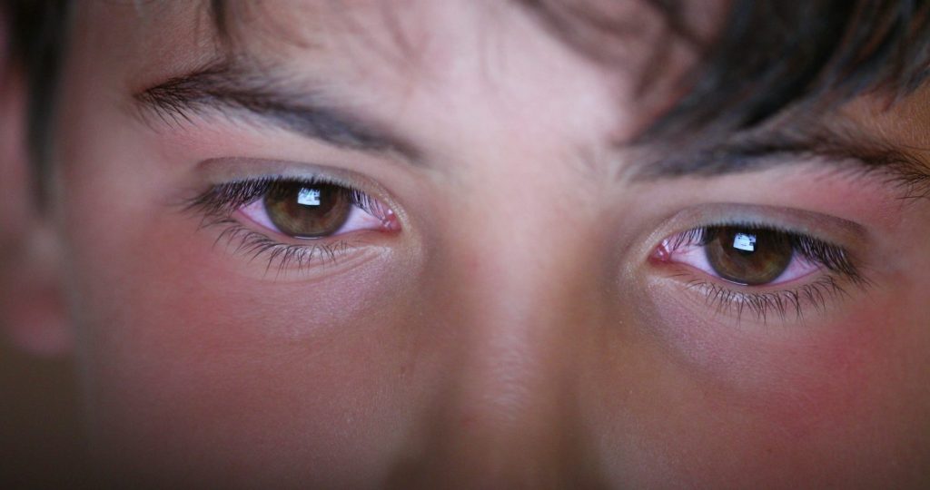 Young boy macro eyes looking at screen device