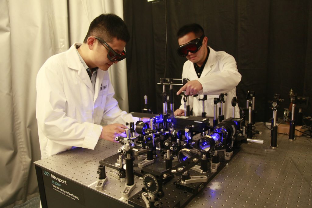 Pictured are researchers Xianglei Liu and Jinyang Liang working on the optical setup. A newly engineered camera that can capture 4.8 million frames per second has been developed - at a fraction of the cost of its commercial contemporaries. PHOTO BY XIANGLEI LIU AND JINYANG LIANG/SWNS 