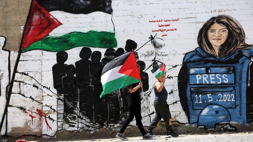 <p>Palestinians walk past a mural for Al Jazeera journalist Shireen Abu Akleh in the West Bank city of Bethlehem, on May 16, 2022. Al Jazeera journalist Shireen Abu Akleh was shot and killed on 11 May 2022 by Israeli forces during an Israeli raid in the West Bank town of Jenin. WISAM HASHLAMOUN/JNS</p>