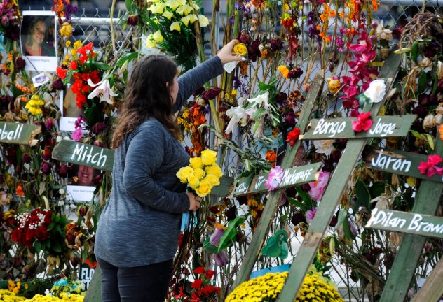 Holly Harmon places a rose into a memorial for victims of Hurricane Ian in Fort Myers, Florida, on Monday, Oct. 10, 2022. More than 100 died during the hurricane, with the greatest number in Lee County. (AP Photo/Jay Reeves)