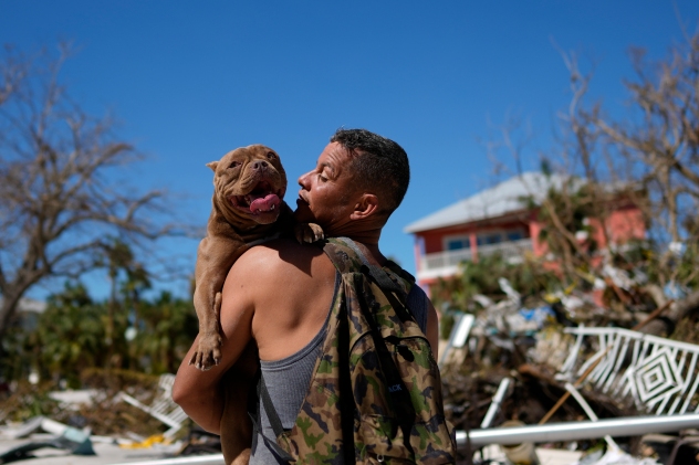 Eduardo Tocuya carries a dog he recovered in hopes of reuniting it with its owners, two days after the passage of Hurricane Ian, in Fort Myers Beach, Fla., Friday, Sept. 30, 2022. (AP Photo/Rebecca Blackwell)