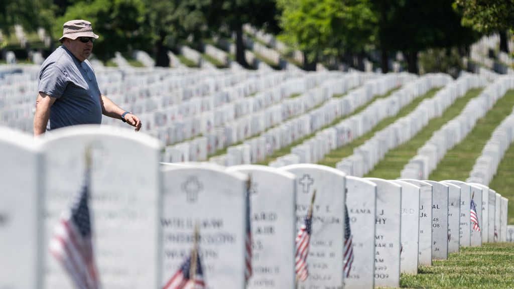 A man walks past headstones, with US national flags in front of them, in section 60 at Arlington National Cemetery before the Memorial Day weekend in Arlington, Virginia on May 26, 2023. Kristoffer Solesbee was in the Airforce as an Explosive Ordnance Disposal Technician, and was killed in Iraq on may 26, 2011 when their unit attacked with in improvised explosive device. ANDREW CABALLERO-REYNOLDS/SWSN RESEARCH